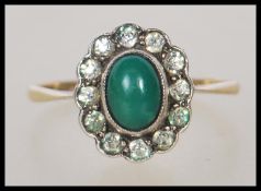 A stamped 9ct gold and silver ring having a gold shank with a silver head set with a central green