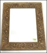 An early 20th Century wall mirror of rectangular form having an embossed brass frame with scallop