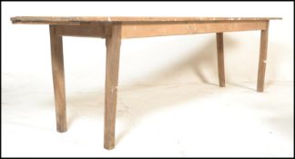 A large 19th century rustic French country pine refectory dining table being raised on squared