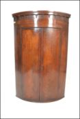 A Georgian 19th Century large mahogany bow front corner cupboard having moulded cornice above twin