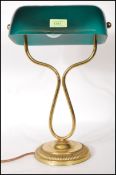 A vintage bankers lamp having a green glass shade raised on a round stepped base with curved brass