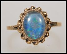 A hallmarked 9ct gold ladies dress ring set with an opalescent stone in w twist design setting.