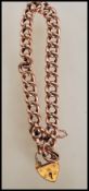 A hallmarked 9ct gold curb link heart padlock bracelet with a safety chain. Hallmarked Birmingham