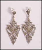 A pair of stamped 925 silver drop earrings of scrolled form set with marcasites. Weight 10.2g.