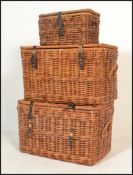 A group of three  20th century graduating wicker laundry / storage wicker baskets having hinged lids