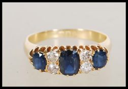 A hallmarked 18ct gold ring set with three sapphires and four round cut diamonds. Hallmarked