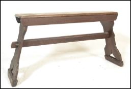 A early 20th Century stained pine bench raised on shaped supports united by a pegged stretcher below