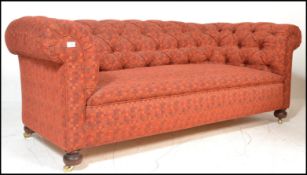 A Victorian  style Chesterfield sofa settee being raised on mahogany turned legs with brass