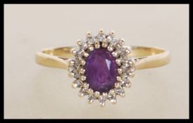 A hallmarked 9ct gold ring set with an oval cut purple stone with a halo of white accent stones.