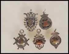 A group of five silver pocket watch albert chain fob medals, two having central armorial 9ct