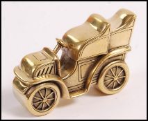 A brass vesta case in the form of a vintage car having a match striker to underneath. Measures 4.2cm