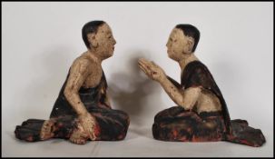 A pair of 20th Century wooden praying Buddhist Monks both in a seated kneeling position having