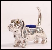 A stamped sterling silver pin cushion in the form of a blood hound with yellow and black glass eyes.