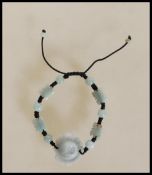 A contemporary Chinese carved jade strung bead bracelet having a large carved lotus flower with