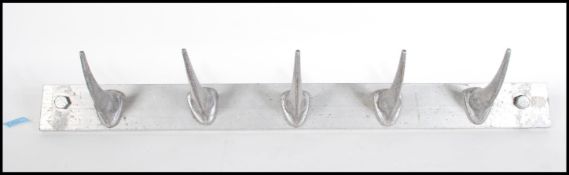 A metal 20th Century wall hanging coat rack having Rhino horn shaped hooks. Five hooks in total.