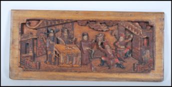 A 19th Century Chinese hand carved wall hanging panel depicting a courtyard scene with red