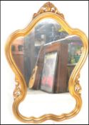 A 20th Century gilt rococo style wall mirror having a symmetrical reeded gilt frame with scrolled