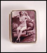 A stamped sterling silver pill box having a enamelled risque image of a woman to the front. Weight