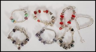 A group of six silver white metal Pandora style snake chain charm bracelets, each adorned with a