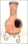 A 20th Century garden terracotta / clay tall Chiminea of bulbous form, set on a scroll work metal