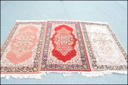 A group of three 20th Century matching floor rug / runners on different coloured grounds, each
