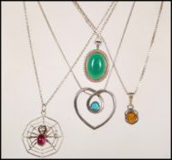 A collection of four silver chain pendant necklaces to include a spider sat upon a wed with