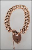 An early 20th Century stamped 9ct gold curb link bracelet having a heart padlock and safety chain.
