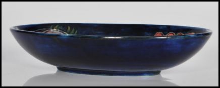 A mid 20th century Moorcroft blue ground ' Hibiscus pattern ' oval dish having a floral pattern.