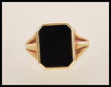 A stamped 585 14ct gold ring set with a square cut onyx panel to the head with reeded shoulders.