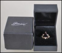 A hallmarked 9ct gold ring having central triangular cut Mozambique garnet with diamond accent.