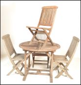 A 20th Century weathered teak folding extendable garden table of circular form with four folding