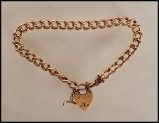 A hallmarked 15ct gold curb link bracelet having a heart padlock and safety chain. Hallmarked