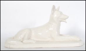 A large early 20th Century monochrome ceramic figurine of a German Shepherd / Alsatian in a seated