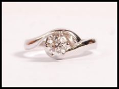 A stamped 750 18ct white gold crossover ring set with a brilliant cut diamond. Weight 3.7g.