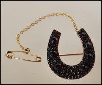 A 19th Century Victorian gold plated brooch in the form of a horseshoe being set with Bohemian