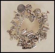 A silver hallmarked charm bracelet having heart padlock clasp with an assortment of silver charms to