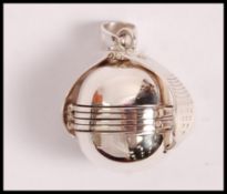 A stamped 925 expandable locket in the form of a sphere, unfolds to reveal four round photo