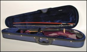 A 20th Century cased student violin, the hollow body having an Aubergine purple finish, cased with