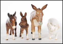 A collection of four ceramic figurines modelled as animals to include a Donkey, another Donkey, a