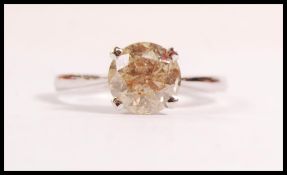 A stamped 18ct white gold solitaire ring prong set with a brilliant cut champagne diamond. Diamond