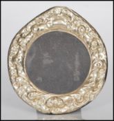 A sterling silver easel back photograph picture frame of circular form having rococo style relief
