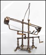 A brass adjustable wine holder/pourer raised on pad paw feet with carrying handle atop. Screw-thread