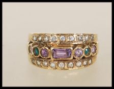 A 9ct gold suffragette style ring set with a row of purple and green stones flanked by two rows of