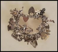 A vintage silver hallmarked charm bracelet having heart padlock clasp with an assortment silver