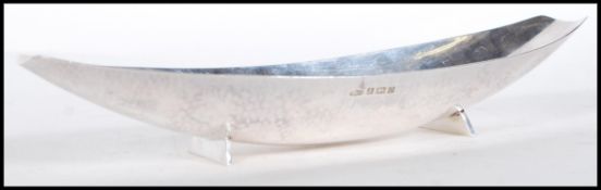 An Arts and Crafts style silver hallmarked dish on stand of boat form having hand hammered finish.