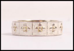A stamped 925 silver white enamelled fleur de lys style ring, having repeating panels with florals