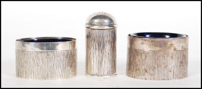 Two silver hallmarked table salts having bark effect decoration and blue glass liners, together with
