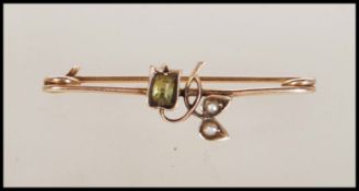 An early 20th Century stamped 9ct gold safety pin brooch having a floral design set with a peridot