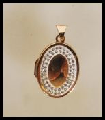 A stamped 375 9ct gold locket pendant of oval form set with a halo of white stones. Weight 2.0g.