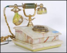 A vintage retro onyx and brass telephone having rotary dial to front, raised on a green stepped